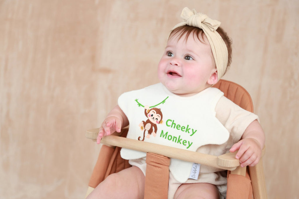Baby wearing a star shaped Dribble Days bib with 'Cheeky Monkey' embroidered on