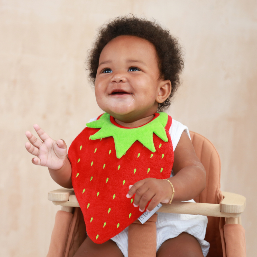Baby wearing a red, strawberry shaped baby bib by Dribble Days