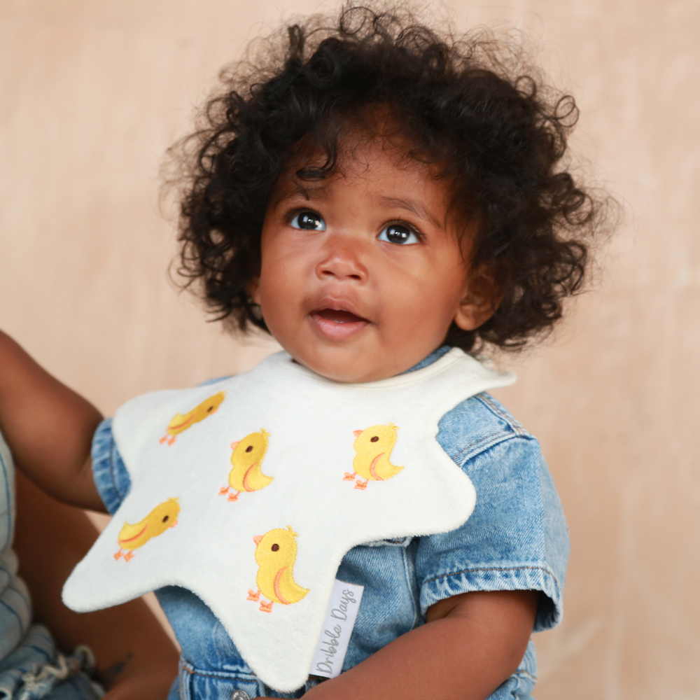Baby wearing a star shaped bib with embroidered yellow chicks
