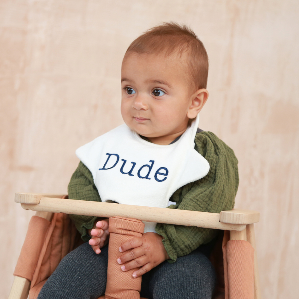 Baby wearing a star shaped bib with DUDE embroidered in navy