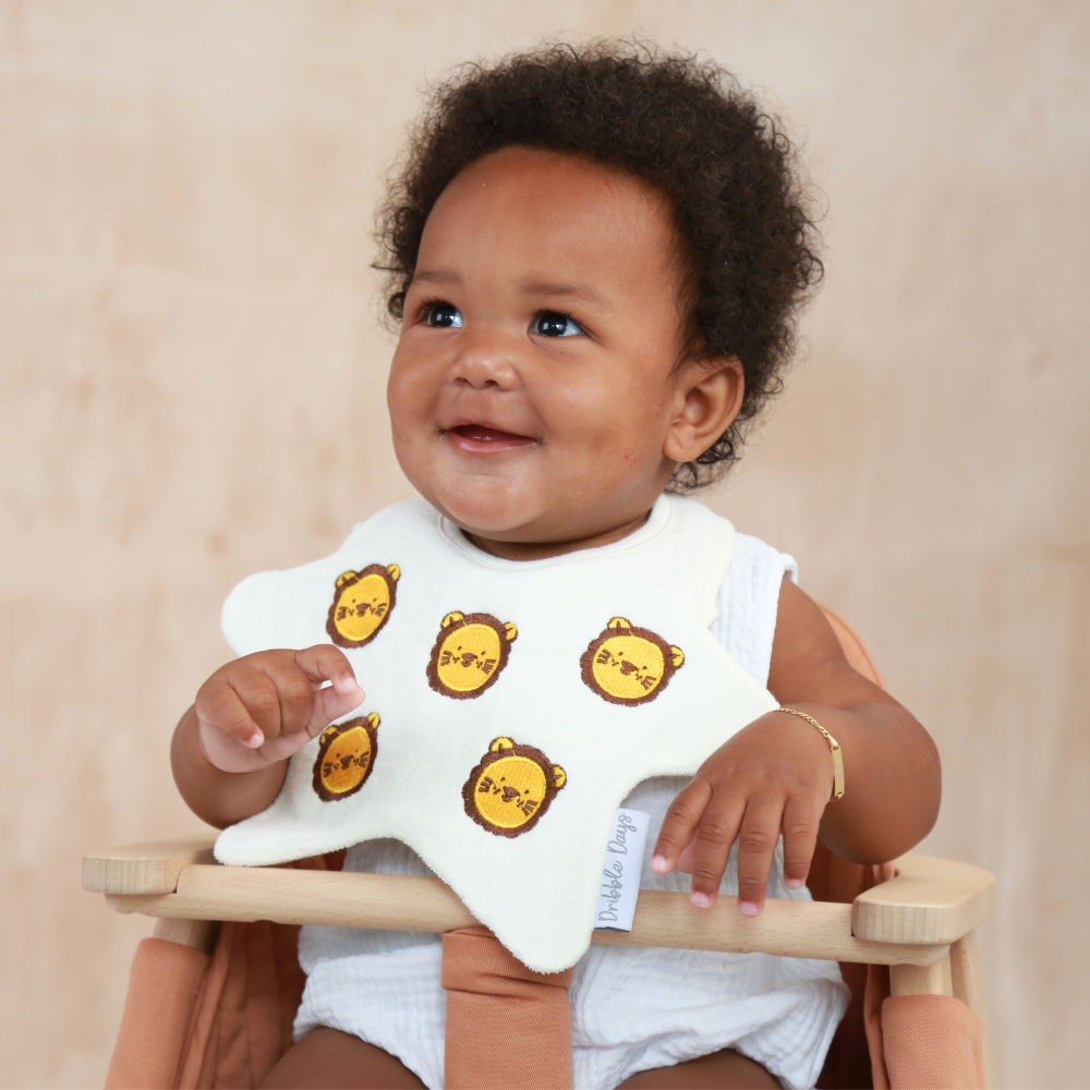 Baby wearing a star shaped bib with embroidered Lions