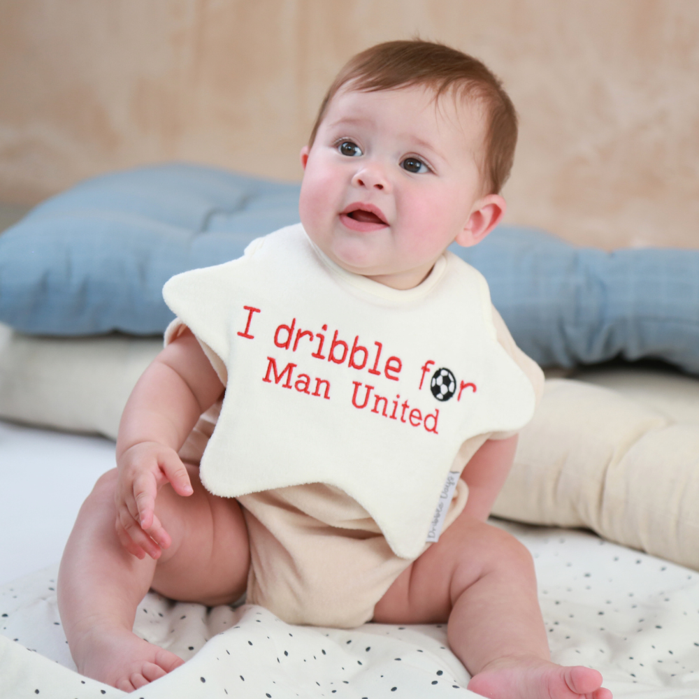 Baby wearing a star shaped football team bib with 'I dribble for Man united' embroidered on