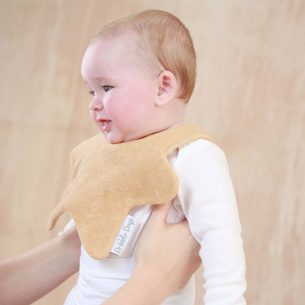 Baby wearing a neutral coloured star shaped bib 