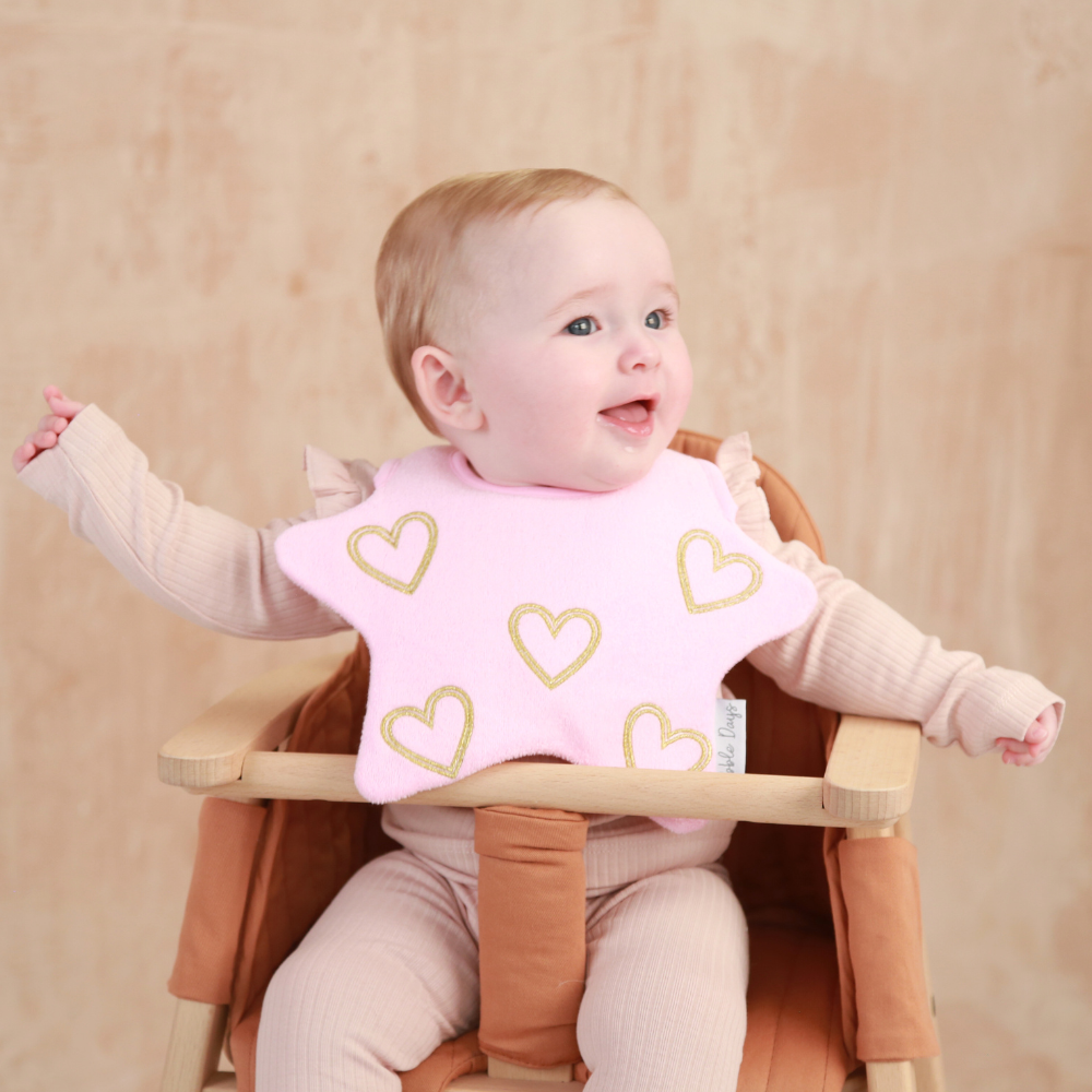 Baby wearing a star shaped bib with an embroidered golden hearts