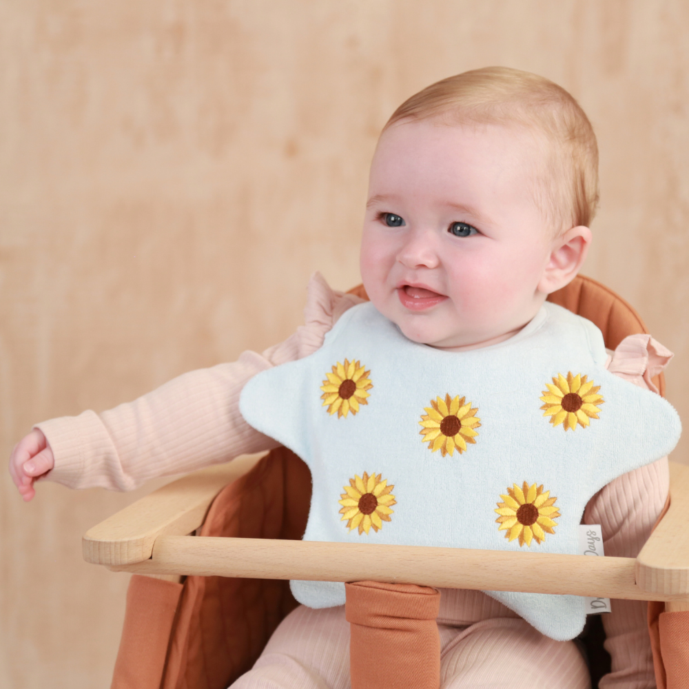 Baby wearing a star shaped bib with embroidered Yellow sunflowers