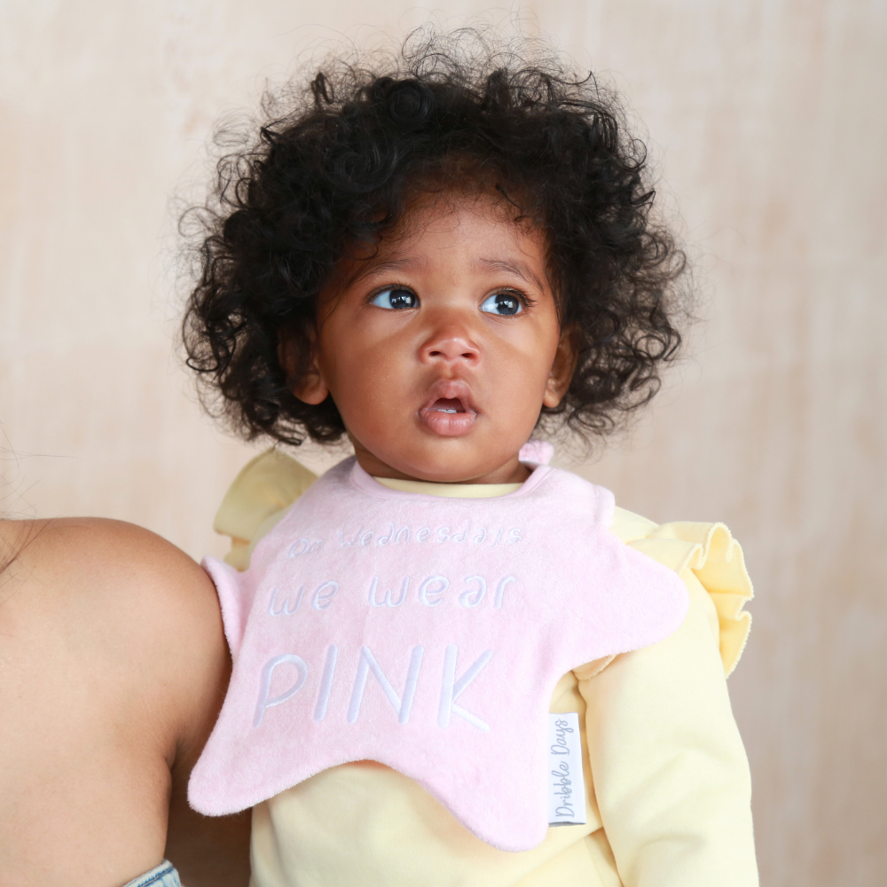 Baby wearing a pink star shaped bib with 'on Wednesdays we wear pink' embroidered on