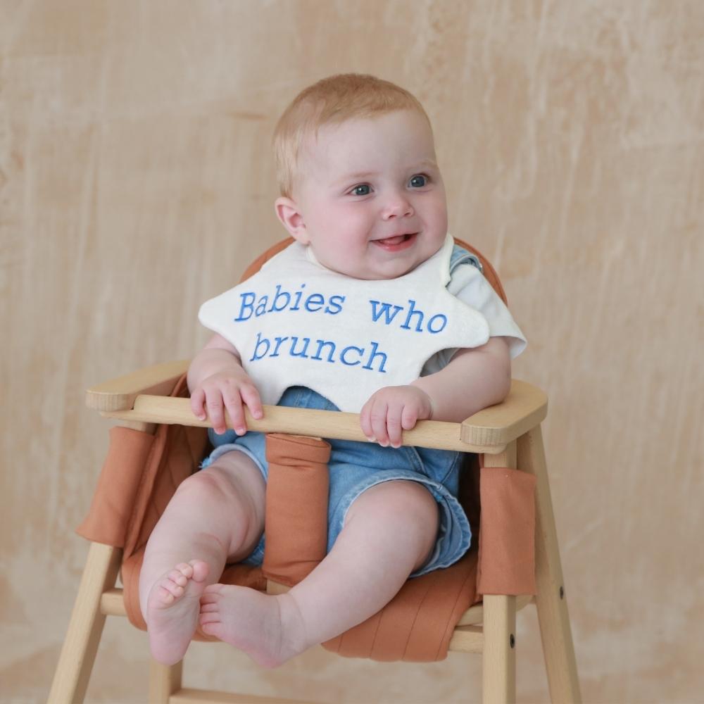 Baby in chair wearing Brunch baby bib