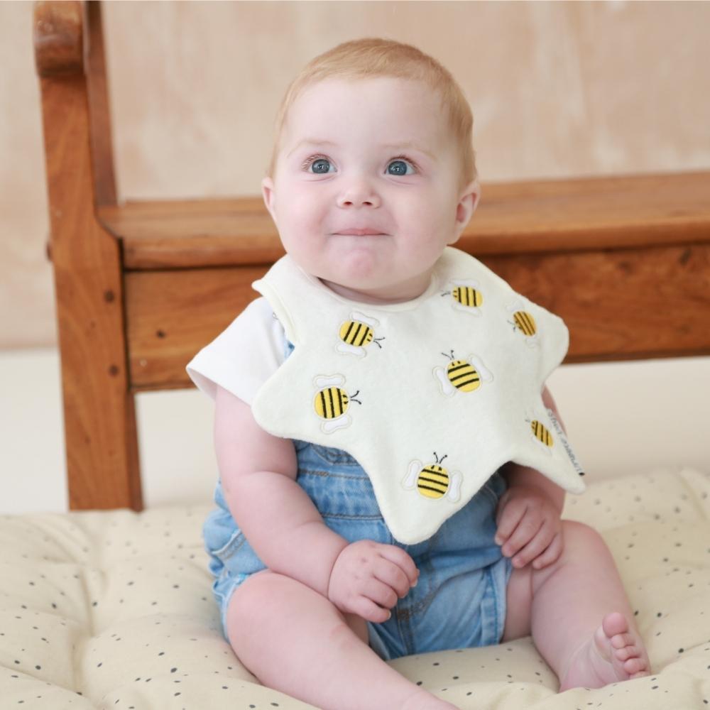 Baby in nursery wearing neutral bumblebee star bib