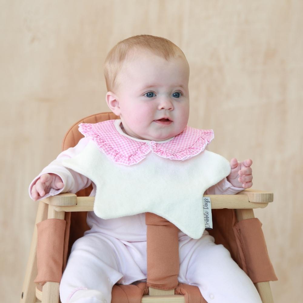 Cream towelling bib with pink collar on baby girl