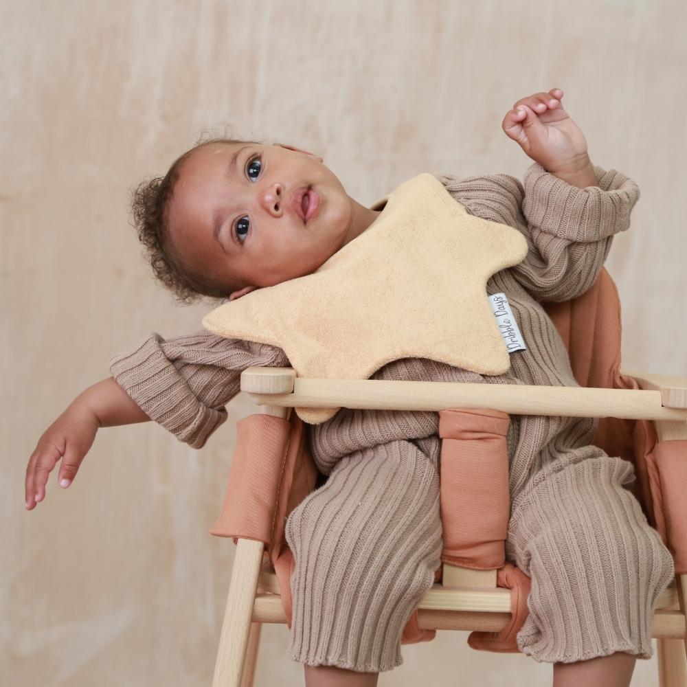 Beige absorbent bib on baby in high chair