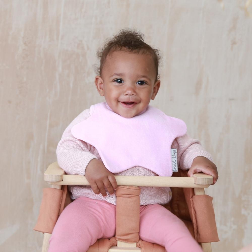 Baby in high chair with pink towelling teething bib